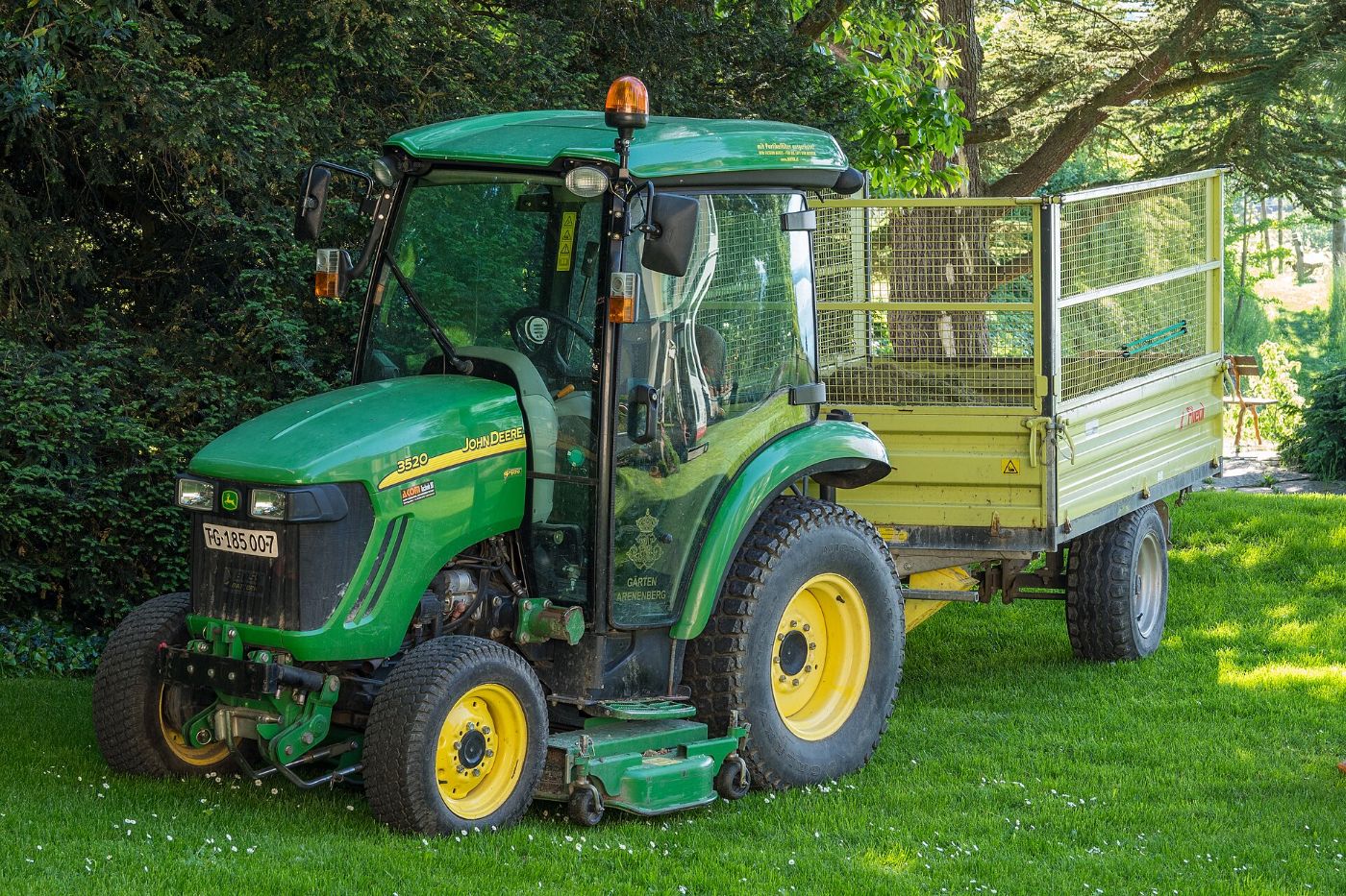 John Deere compact tractor with a mower deck on a trimmed lawn
